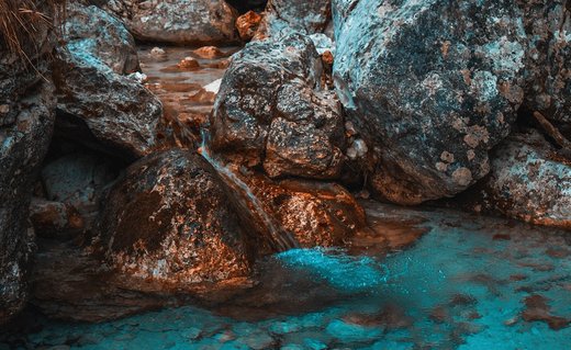 Midden in de rivier vormen keien en grote stenen een bassin voor stilstaand water dat opnieuw begint te stromen als er een steen verlegd wordt. 